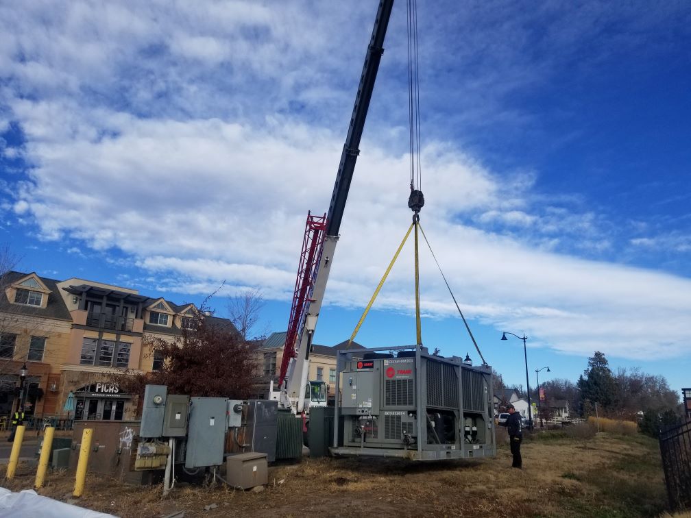 A crane lifting an ice rink chiller into position.
