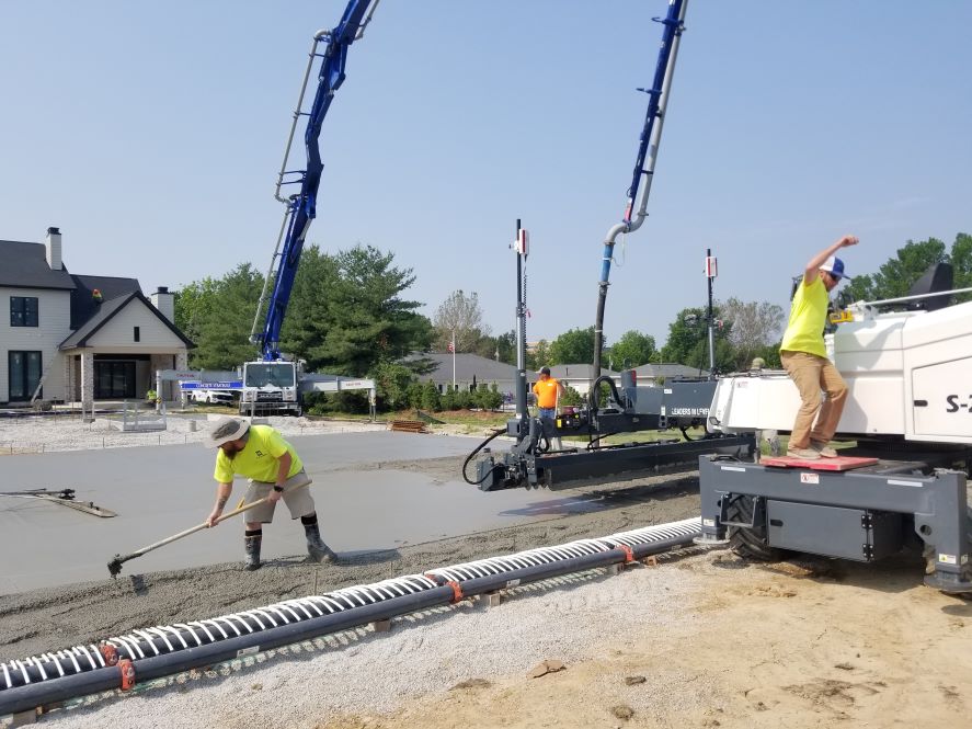 Construction crews spreading concrete over ice rink refrigeration piping.